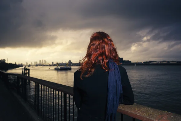 Frau bewundert Sonnenuntergang über Fluss in Stadt — Stockfoto