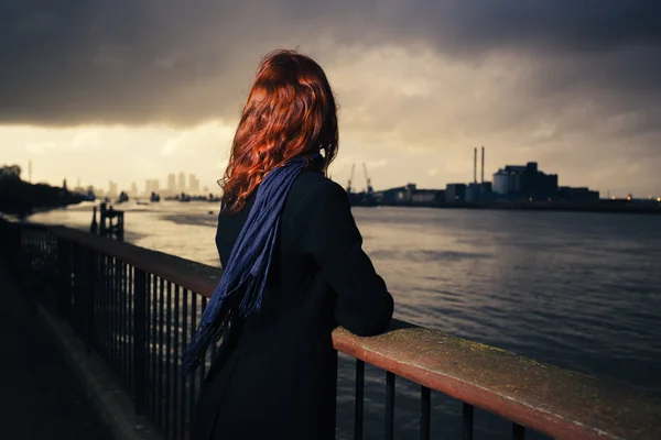 Mujer admirando la puesta de sol sobre el río en la ciudad — Foto de Stock