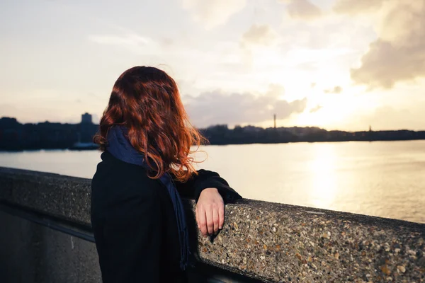 Mujer admirando la puesta de sol sobre el río en la ciudad — Foto de Stock
