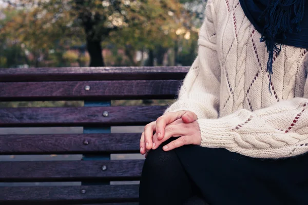 Young woman sitting on park bench — Stock Photo, Image