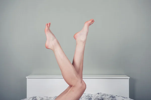 Mujer acostada en la cama con las piernas levantadas — Foto de Stock