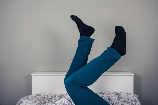 Homem na cama com as pernas levantadas — Fotografia de Stock