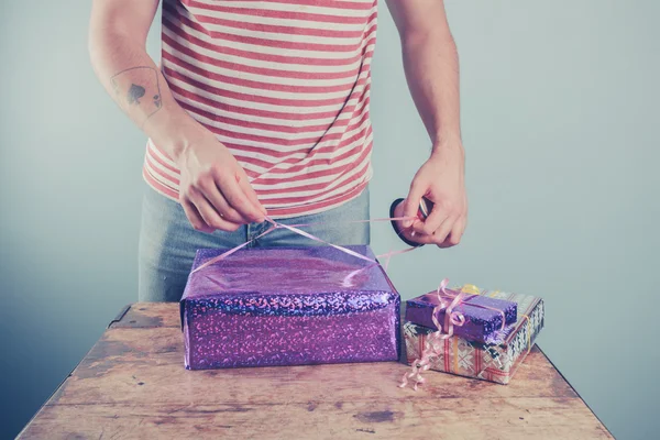 Man at table wrapping presents — Stock Photo, Image