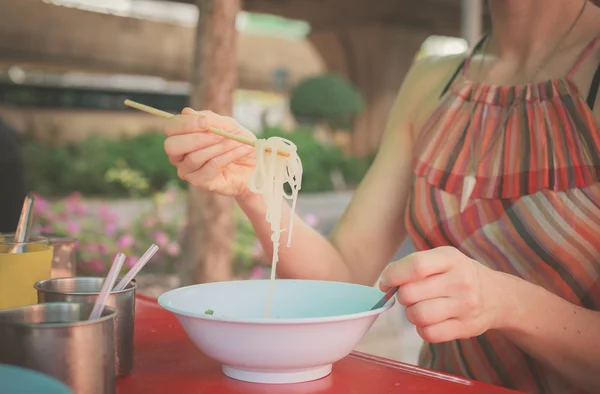 Woman eating noodles in the street