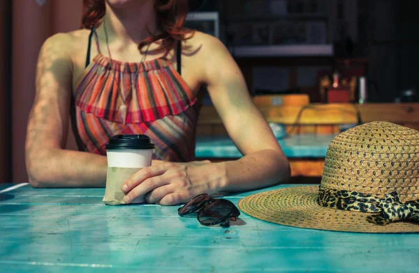 Vrouw met hoed koffie drinken in café — Stockfoto