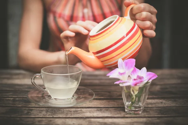 Young woman pouring tea at table — Stock Photo, Image