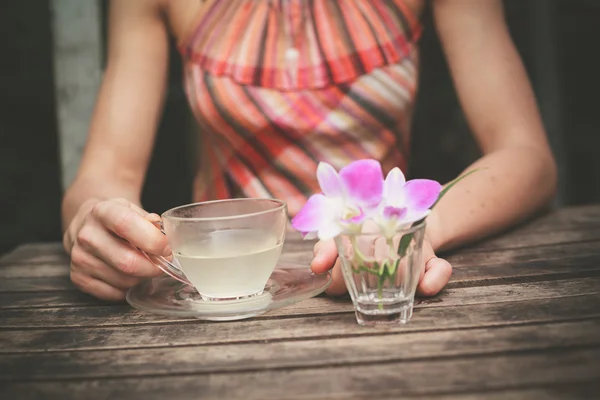 Jovem mulher bebendo chá à mesa — Fotografia de Stock