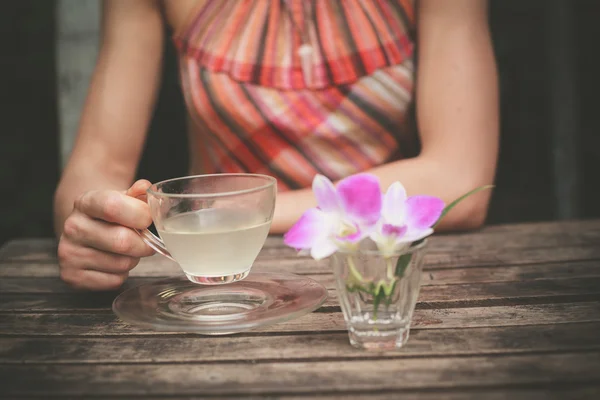 Jovem mulher bebendo chá à mesa — Fotografia de Stock