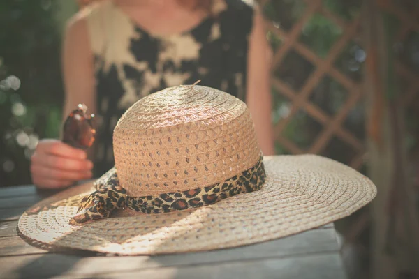 Young woman sitting at a table with a hat — Stock Photo, Image