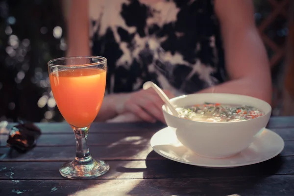 Kadın masada çorba ve bardak meyve suyu ile — Stok fotoğraf