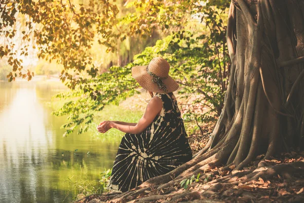 Woman sitting under tree by the river — Stock Photo, Image