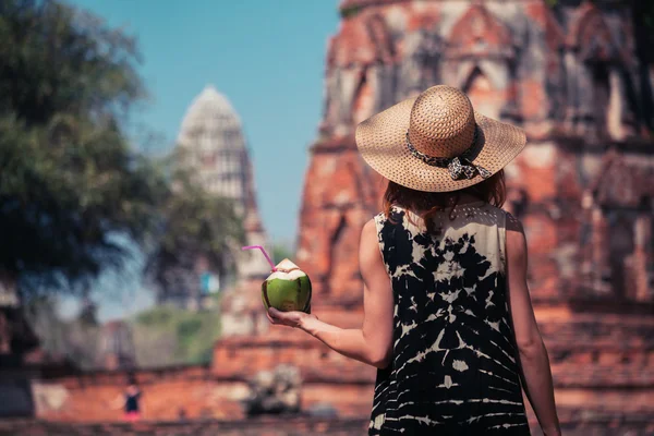 Woman drinking coconut juice by ancient temple — Stock Photo, Image