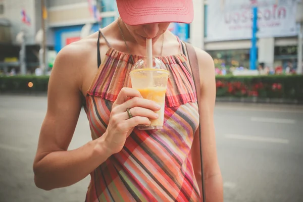 Jonge vrouw drinken sap in de straat — Stockfoto