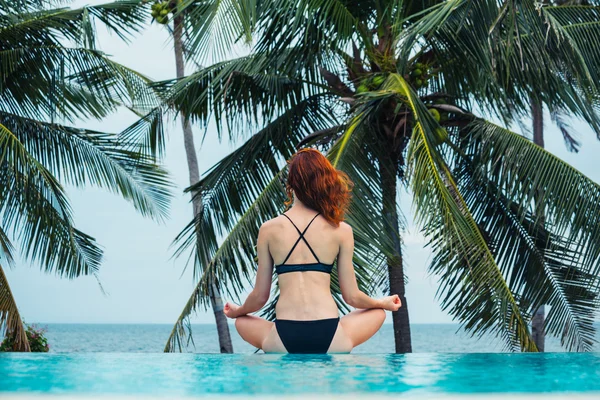 Mulher jovem meditando por piscina — Fotografia de Stock