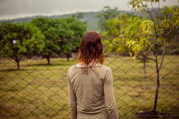 Mujer joven por valla en la granja — Foto de Stock