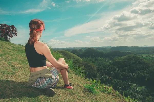 Mujer joven sentada en una colina y admirando la vista —  Fotos de Stock