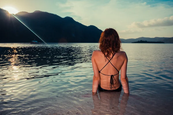 熱帯のビーチの上に座って水着の若い女性 — ストック写真