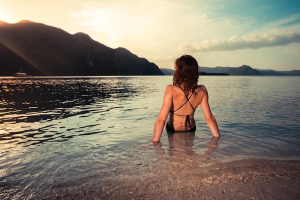 Jovem de maiô sentada na praia tropical — Fotografia de Stock