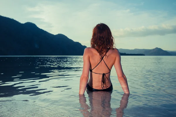 年轻的女人坐在热带海滩上的泳装 — 图库照片