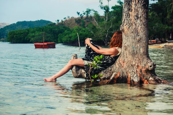 Kvinna sitter upp mot träd på tropical beach — Stockfoto