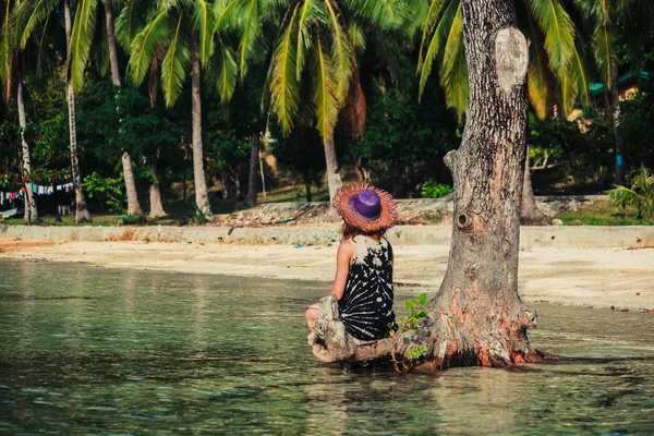 Woman sitting up against tree on tropical beach — Stock Photo, Image