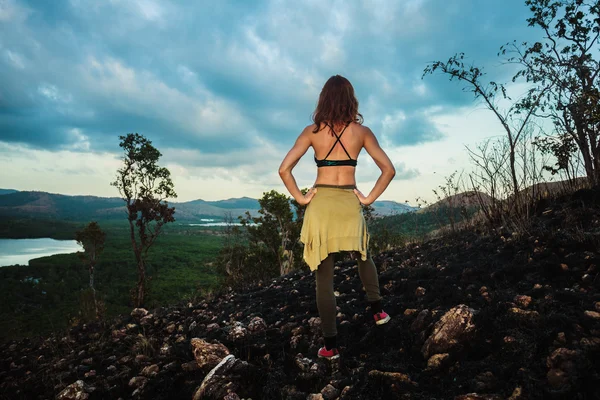 Mulher de pé em uma colina queimada em um clima tropical — Fotografia de Stock