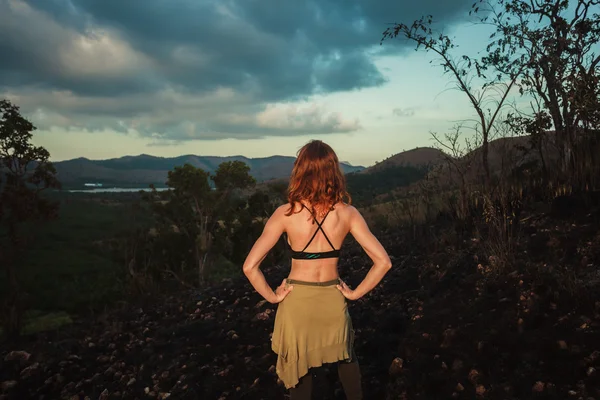 Mulher de pé em uma colina queimada em um clima tropical — Fotografia de Stock