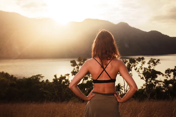 Jovem mulher admirando o pôr do sol sobre a baía — Fotografia de Stock