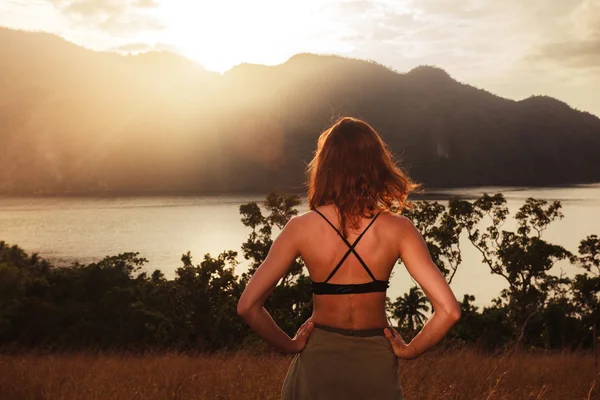 Jovem mulher admirando o pôr do sol sobre a baía — Fotografia de Stock