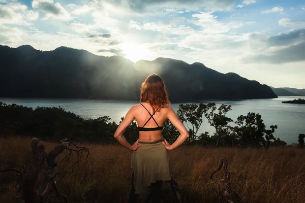 Young woman admiring sunset over bay — Stock Photo, Image