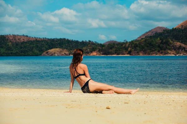 Krásná mladá žena uvolňující na tropické pláži — Stock fotografie