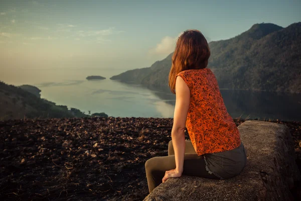 Güneş doğarken alışılmadık kayaya oturan kadın — Stok fotoğraf