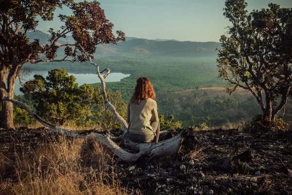 Vrouw zitten op een heuvel bij zonsopgang — Stockfoto
