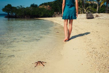 Bir deniz yıldızı kumsalda yürüyen kadın