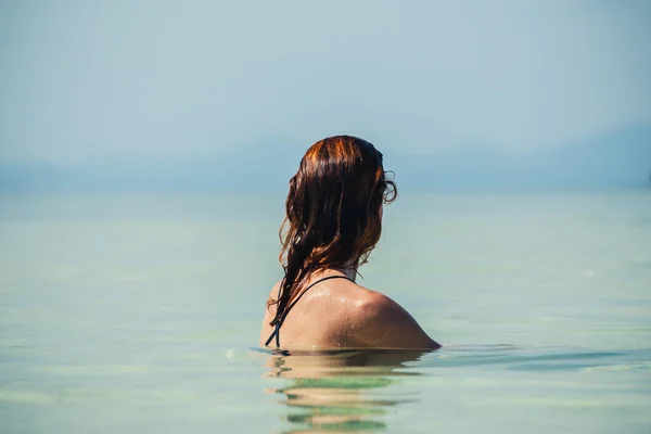 Woman sitting in water by beach — Stock Photo, Image