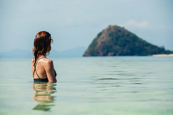 Mulher sentada na água olhando para a ilha — Fotografia de Stock