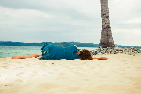 Young woman lying under palm tree on beach — Stock Photo, Image