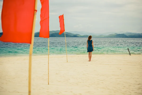 Woman on tropical beach with flags — Stock Photo, Image