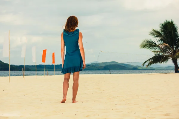 Женщина на тропическом пляже с флагами — стоковое фото