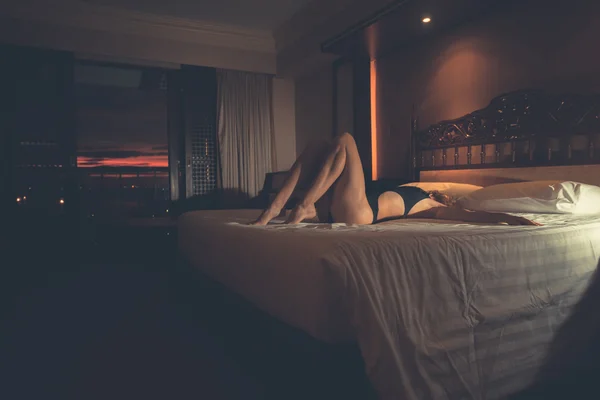 Sexy žena na lůžko v hotelu při západu slunce — Stock fotografie