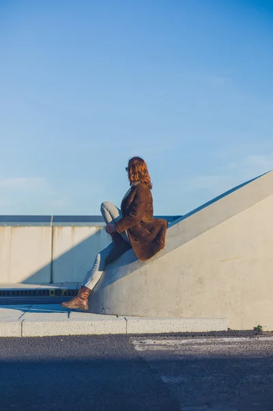 Woman sitting on barrier in the road — Stock Photo, Image