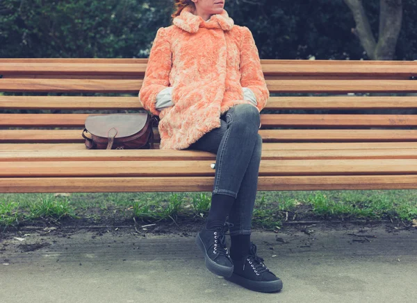 毛皮のコートのベンチに座っている女性 — ストック写真