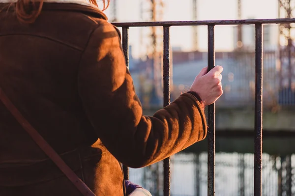 Woman grabbing a fence by a canal — Stock Photo, Image