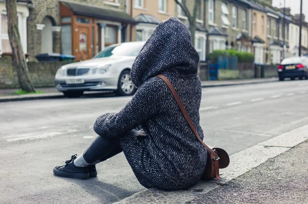 Mladá žena sedící iontů na ulici — Stock fotografie