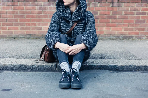 Mladá žena sedící iontů na ulici — Stock fotografie