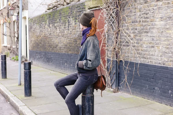 Woman sitting on a bollard in the street — Stock Photo, Image