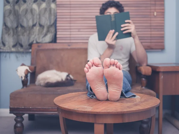 Barefoot man thuis lezen — Stockfoto