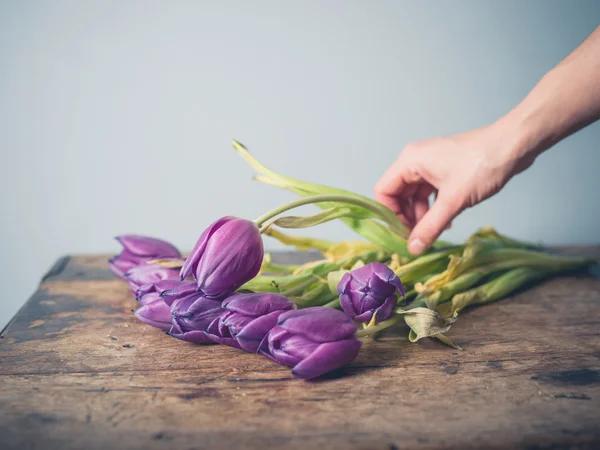 Hand picking up dead flowers from table — Stock Photo, Image