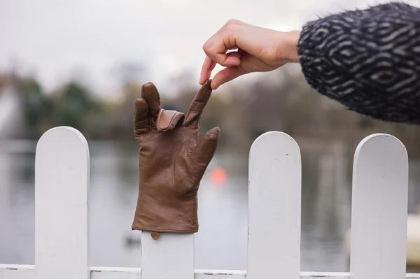 Hand picking up glove from a fence — Stock Photo, Image