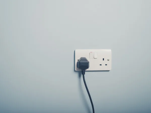 UK wall socket and cord on blue wall — Stock Photo, Image